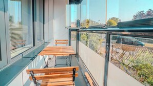 Ein Balkon mit Glasgeländer, Holzbanken und Blick auf die Umgebung.