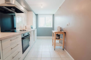 A modern kitchen with a built-in oven, a microwave, and a coffee maker on a wooden shelf. - Free Parking 2BR Sleeps 5 Close to JR Hospital (Headington)