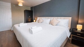 A hotel room with a large bed, bedside lamps, and a wardrobe. - Free Parking 2BR Sleeps 5 Close to JR Hospital (Headington)