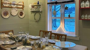 Uma sala de jantar com uma mesa posta para refeição, com pratos, copos e um arranjo central.