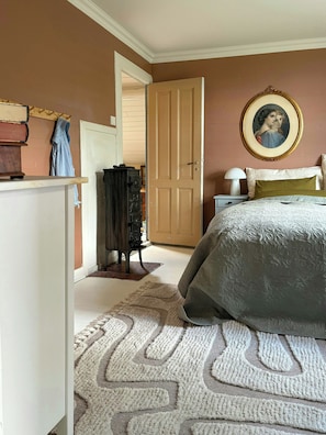 Ein Schlafzimmer mit einem Bett, einer Kommode, einer Tür zu einem anderen Raum und einem gerahmten Bild an der Wand.