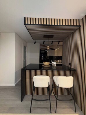 A modern kitchen with a black and white striped backsplash, a central island with stools, and a visible kitchen counter. - Luxury 3BR Apartment  2 Baths Near Lisbon & Sintra (Queluz)