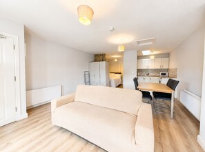 A modern apartment with a living room, kitchenette, and a dining area.