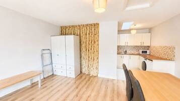 A compact kitchen with white cabinets, a wooden dining table, and a bench.