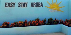 A wall with the text "EASY STAY ARUBA" and a sun emblem. - Cozy 1-bedroom apartment 3 km from Eagle beach (Noord)
