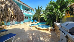 A backyard with a swimming pool, a hot tub, and a grill. - Cozy 1-bedroom apartment 3 km from Eagle beach (Noord)