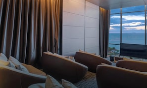 A modern living room with a large window offering a view of the sea. There are two sofas and a small table with a TV. - 2 Bed Room Rare Unit With Bath Tub Sea View (Pattaya City)