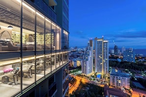 A modern hotel with a glass facade, a rooftop lounge with seating, and a city view. - 2 Bed Room Rare Unit With Bath Tub Sea View (Pattaya City)