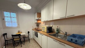 A compact kitchen with white cabinets, a wooden countertop, a sink, and a window with a grid pattern.