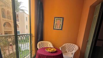 Een balkon met een tafel en stoelen, uitzicht op gebouwen, en een deur.