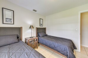 Ein Schlafzimmer mit zwei Betten, einem Nachttisch, einer Lampe und zwei gerahmten Bildern an der Wand.