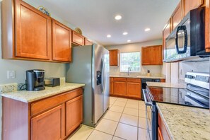 A kitchen with wooden cabinets, stainless steel appliances, a coffee maker, and a window with blinds. - 6 Mi to Dtwn! Centrally Located Sarasota Home (Sarasota)