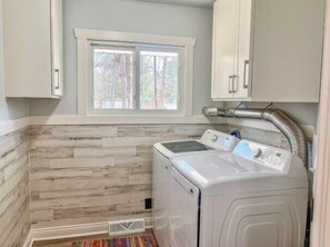 A laundry room with a washing machine, a window, and wooden wall paneling. - *NEW*Peaceful Retreat-Firepit-WI Dells-Castle Rock (Mauston)