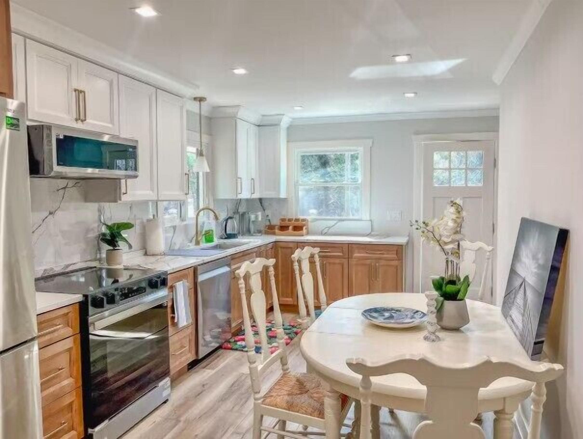 A modern kitchen with white cabinetry, a dining table with chairs, and a window providing natural light.