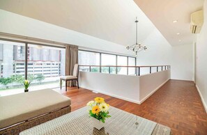 A modern living room with a balcony, large windows, and a hanging light fixture. - Beachfront Duplex in Jomtien 3BR with Pool & Gym. Sea view & Night market. 8ppl (Pattaya City)