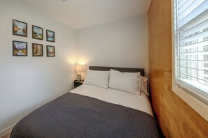 A bedroom with a bed, a nightstand, a lamp, and a window with blinds. - Walk to Dtwn Sandpoint! Family Gem w/ Patio & Yard (Sandpoint)