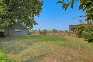 A residential backyard with a house, a wooden fence, and a grassy lawn. - Walk to Dtwn Sandpoint! Family Gem w/ Patio & Yard (Sandpoint)