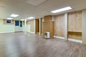 Une pièce spacieuse avec un plancher en bois, un climatiseur blanc et une cloison en bois.