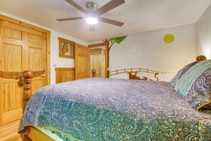 Un dormitorio con una cama, armario de madera y ventilador de techo.