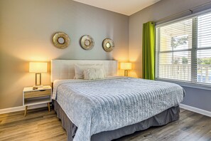 A bedroom with a bed, two bedside tables, a window with blinds, and wall decor. - Near Grand Boulevard & Beaches! Coastal Condo (Miramar Beach)