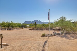 A paved area with a flagpole, a lamp post, and a fenced section with desert vegetation. - Brand New Casita by Superstition Mtns: Patio (Apache Junction)