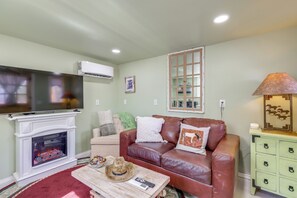 A living room with a fireplace, leather sofa, television, and a decorative lamp. - Brand New Casita by Superstition Mtns: Patio (Apache Junction)