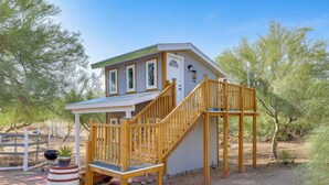 A small, single-story building with a wooden staircase leading to a porch. - Brand New Casita by Superstition Mtns: Patio (Apache Junction)