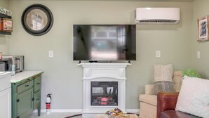 A living room with a flat-screen TV mounted above a white fireplace, a green cabinet with a microwave, and a fire extinguisher on the floor. - Brand New Casita by Superstition Mtns: Patio (Apache Junction)