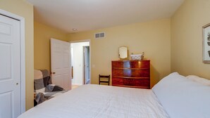 Een slaapkamer met een bed, een kaptafel en een deur naar een andere kamer.
