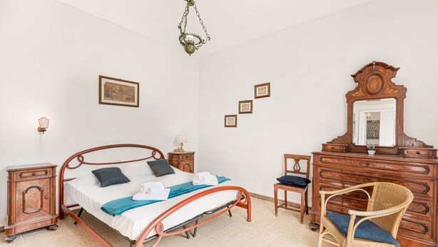 A bedroom with a metal-framed bed, a wooden dresser, a chair, and a hanging light fixture. - [VillinoAuroraVI] Near the station 5TERRE/Garden (La Spezia)
