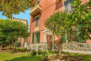 A building with a balcony, a table with chairs, and a garden area with trees and shrubs. - [VillinoAuroraVI] Near the station 5TERRE/Garden (La Spezia)