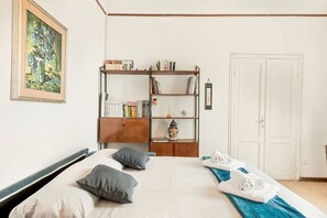 A hotel room with a bed, pillows, a bookshelf, a door, and a painting on the wall. - [VillinoAuroraVI] Near the station 5TERRE/Garden (La Spezia)
