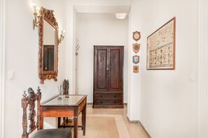 A hallway with a wooden door, a mirror with wall sconces, a framed picture, and a small table with a chair. - [VillinoAuroraVI] Near the station 5TERRE/Garden (La Spezia)