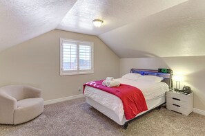 Een slaapkamer met een bed, een stoel, een nachtkastje, een klok en een raam.