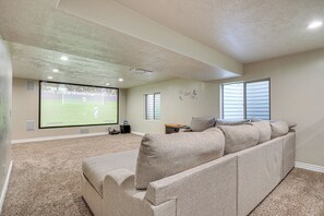 Ein Heimkinozimmer mit einer großen Leinwand, einem Ecksofa und einem Teppichboden.