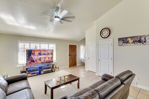 Ein Wohnzimmer mit Fernseher, Ledersofas, einem Couchtisch und einem Deckenventilator.
