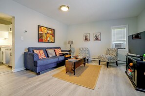 A living room with a sofa, armchair, coffee table, and artwork on the walls. - Near Hospitals & Colleges! Stylish St Paul Apt (St Paul)