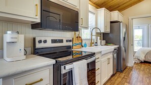A modern kitchen with white cabinetry, a built-in oven, a microwave, and a stainless steel refrigerator.