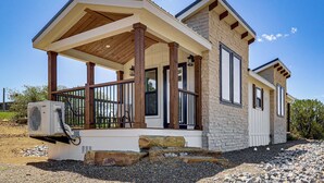 A modern house with a covered porch, stone exterior, and an air conditioning unit.