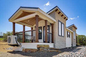 A modern house with a covered porch, stone exterior, and an air conditioning unit.