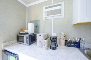 A kitchen with a microwave, toaster, coffee maker, and utensils on the counter. - Charming & Bright Tiny Home: Stadium, River, Metro (Washington)