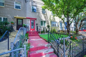 A residential building with a red door, a small front yard with a red pathway, and a metal fence. - Charming & Bright Tiny Home: Stadium, River, Metro (Washington)