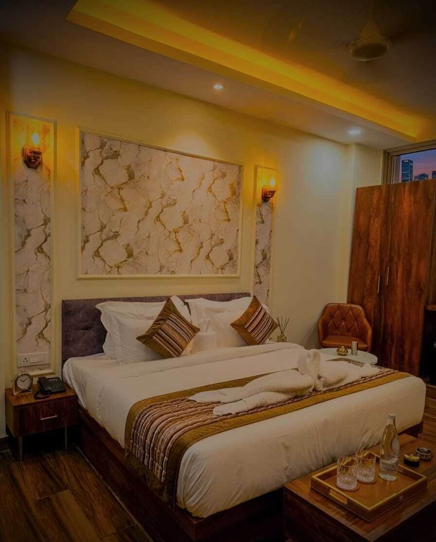 Ein Hotelzimmer mit einem großen Bett, einem Nachttisch, Holzboden und Blick auf die Stadt durch das Fenster.