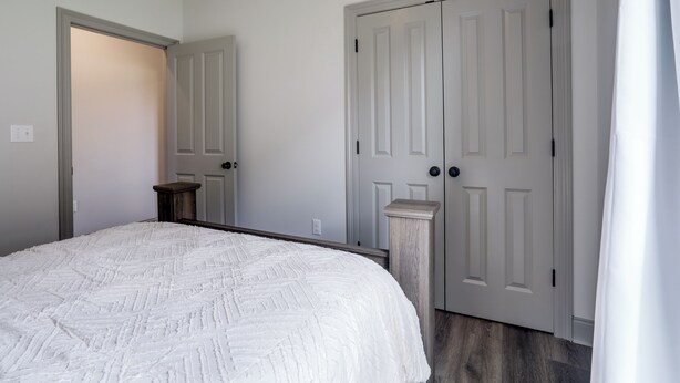 Un dormitorio con una cama, dos puertas, un interruptor de luz y un enchufe.