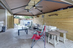 Ein überdachter Patio-Bereich mit Deckenventilator, einer Poolleiter, Gartenmöbeln und einem Schild mit der Aufschrift 'MY HAPPY PLACE'.