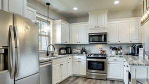 Una cocina moderna con armarios blancos, electrodomésticos de acero inoxidable y piso de madera.