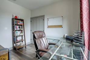 Un bureau à domicile équipé d’un fauteuil en cuir, d’un bureau en verre, d’une bibliothèque et d’un calendrier effaçable.