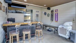 Una zona de bar con taburetes, una barra y un ventilador.