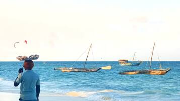Une plage où plusieurs bateaux sont amarrés et où une personne se tient sur le rivage.