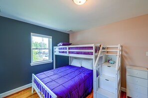 A room with a bunk bed, a window, and a dresser.
